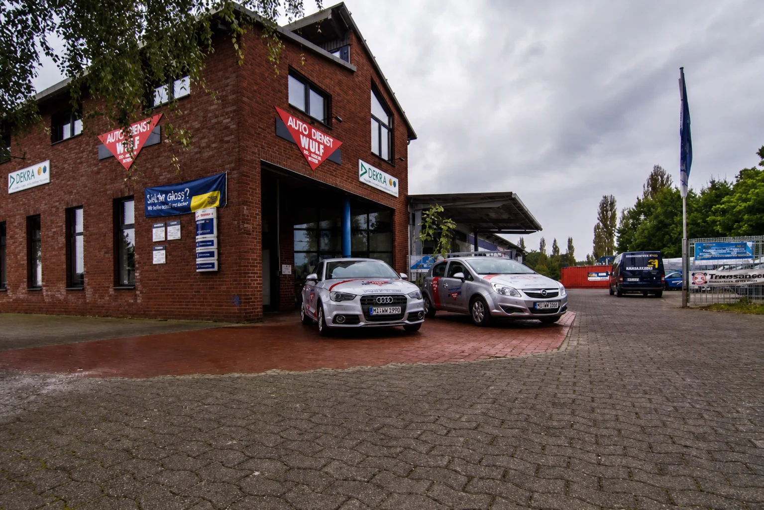 Außenansicht von Wulf's Auto-Schnell-Service in Espelkamp mit Werkstattgebäude und Kundenparkplatz